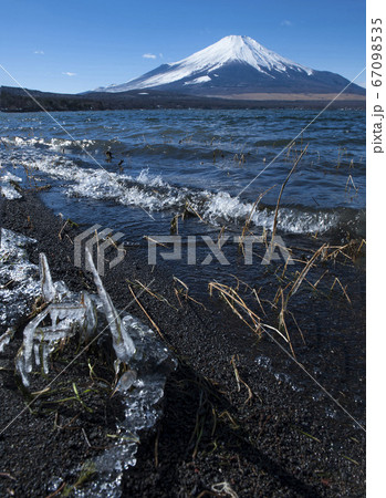 湖畔を打つ波が凍る厳冬期の山中湖と雪を頂く富士山の写真素材