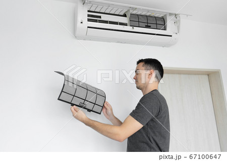 The guy cleans the filter of the home air The guy cleans the filter of the home air 67100647