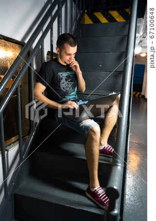 A young man works on a laptop on the deck of a 67100648
