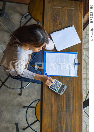 Asian freelancer work from home with calculator and document 67102496