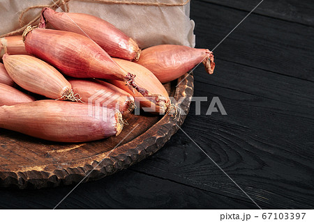 Onion shallot on a black, dark background. Eating vegetables and eating healthy. Eating shallots, adding to various dishes, diversifying food. Onion shallot on a black, dark background. Eating vegetables and eating healthy. Eating shallots, adding to various dishes, diversifying food. 67103397