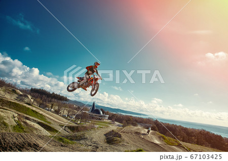 Extreme concept, challenge yourself. Extreme jump on a motorcycle on a background of blue sky with clouds. Copy space, all or nothing. 67103425