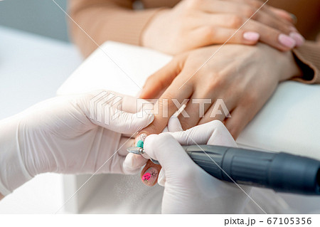Manicure master uses an electric nail machine Manicure master uses an electric nail machine 67105356
