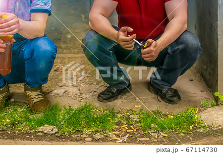 alcoholics, smokers and bad guys sit on the street near cigarette butts alcoholics, smokers and bad guys sit on the street near cigarette butts 67114730