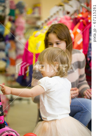 Little girl in pretty dress and her mom at the children's clothes shop 67115261