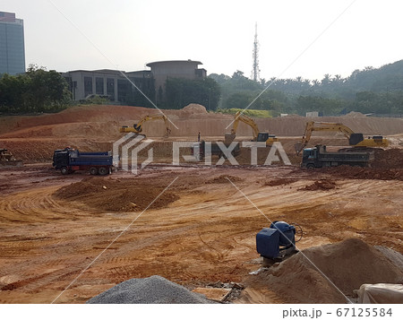 KUALA LUMPUR, MALAYSIA -JULY 17, 2019: Heavy machinery doing the soil backfilling work at the construction site. Works carried out before building construction starts to get the required levels. KUALA LUMPUR, MALAYSIA -JULY 17, 2019: Heavy machinery doing the soil backfilling work at the construction site. Works carried out before building construction starts to get the required levels. 67125584
