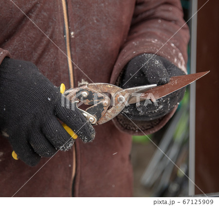 Worker scissors metal at a construction site 67125909