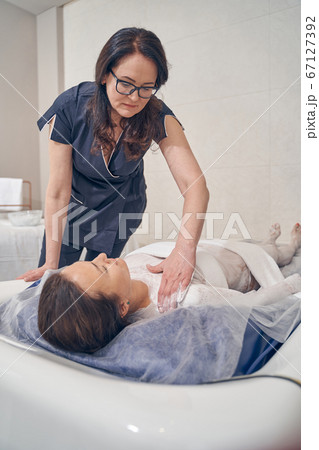 Careful beautician preparing her client for the floating procedure 67127392