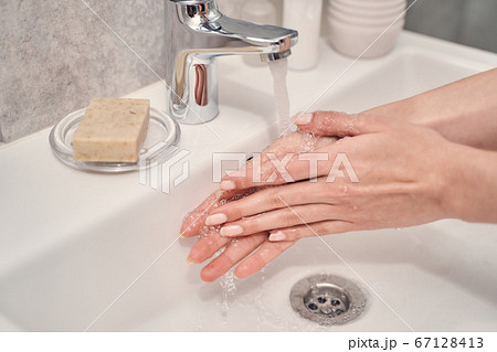 Young Caucasian lady performing a handwashing procedure Young Caucasian lady performing a handwashing procedure 67128413