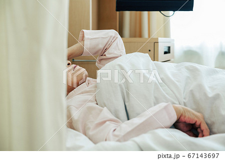 入院先のベッドに横たわる女性 病院 の写真素材