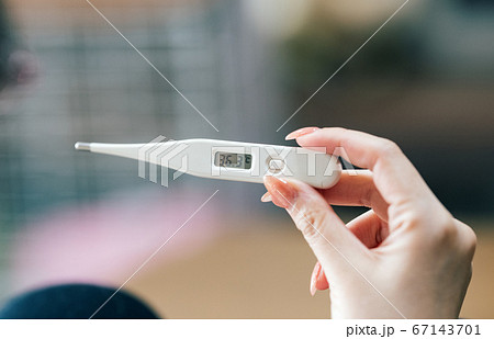 体温計で熱をはかる女性の写真素材
