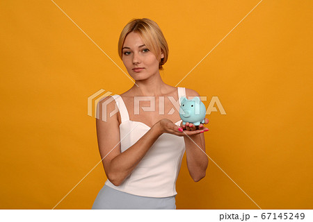 Beautiful young girl holding a pig piggy bank on Beautiful young girl holding a pig piggy bank on 67145249