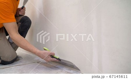 Worker puts putty on the tool. Close-up of a woman's hand with a metal spatula for applying stucco on the wall Worker puts putty on the tool. Close-up of a woman's hand with a metal spatula for applying stucco on the wall 67145611