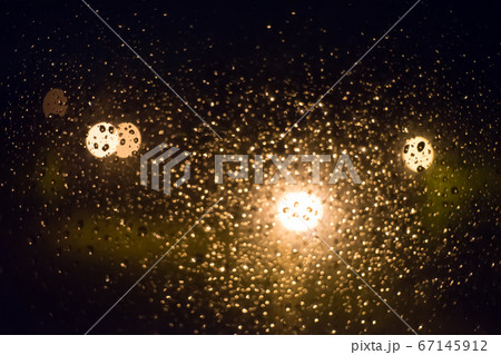 Drops of rain on window glass, lanterns in the 67145912