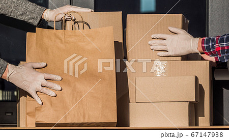 Couriers in protective gloves put parcels on the doorstep of the house Couriers in protective gloves put parcels on the doorstep of the house 67147938