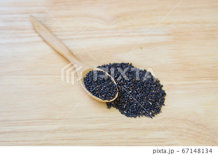 Black sesame seeds in wooden spoon pile on wood 67148134