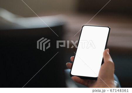 Young woman sitting in chair with modern smartphone with white screen 67148361