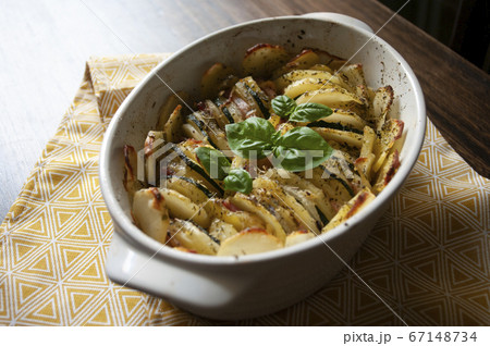 Hearty potato gratin bacon and zucchini,freshly served from the oven on a wooden table.Casserole food,vessel. Photo recipe. Hearty potato gratin bacon and zucchini,freshly served from the oven on a wooden table.Casserole food,vessel. Photo recipe. 67148734