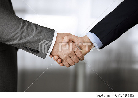 Business people in office suits standing and shaking hands, close-up. Business communication concept. Handshake and marketing Business people in office suits standing and shaking hands, close-up. Business communication concept. Handshake and marketing 67149485