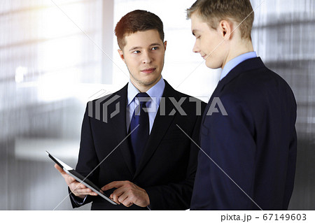Business people discussing something while sitting in sunny office. Focus at businesswoman while talking to her male colleague 67149603