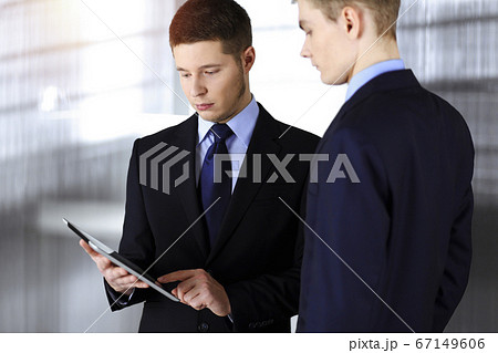 Business people discussing something while sitting in sunny office. Focus at businesswoman while talking to her male colleague 67149606