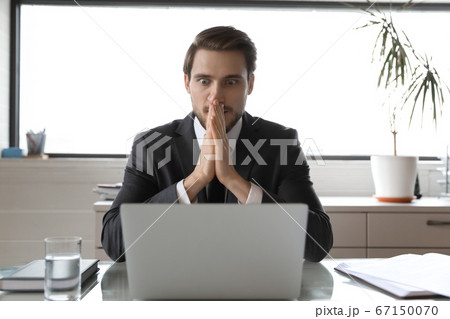 Amazed businessman shocked by online financial news on laptop Amazed businessman shocked by online financial news on laptop 67150070