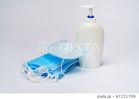 bottle of lotion, sanitizer or liquid soap and protective mask over light grey background 67151709