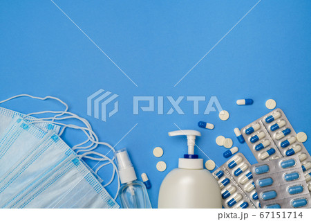 medical protective face masks, hand sanitizer gel and spay for hygiene and pills on blue background 67151714
