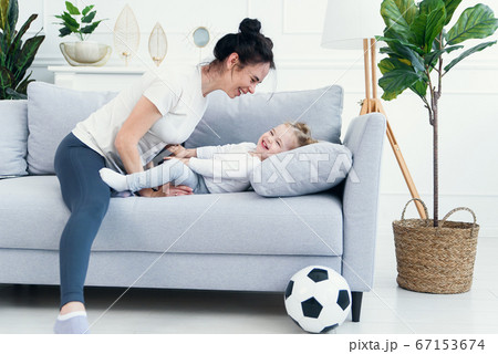 mom and her daughter lying on the couch in the living room. mom and her daughter lying on the couch in the living room. 67153674