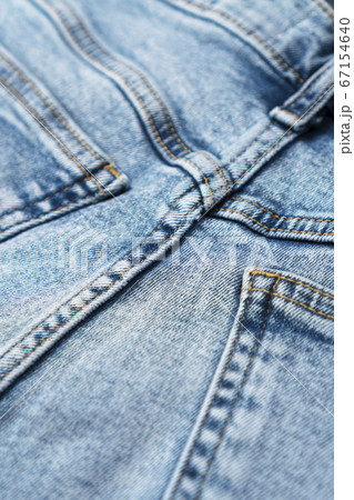 Close-up of denim blue fabric with pockets and yellow seams. Fashionable jeans. Front view. 67154640