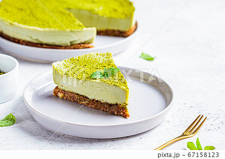 Piece of raw vegan matcha cake on a gray plate. Piece of raw vegan matcha cake on a gray plate. 67158123