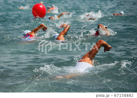 Competitors swimming out into open water at the beginning of triathlon Competitors swimming out into open water at the beginning of triathlon 67158882