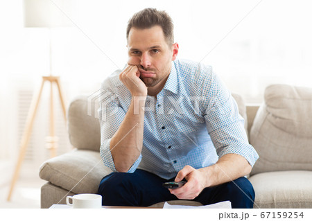 Bored man watching TV at home, holding remote control Bored man watching TV at home, holding remote control 67159254