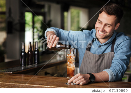 Alcoholic cocktail in pub interior. Barman pours beer in high glass 67159699