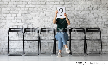Anonymous woman hiding her face behind paper with question mark Anonymous woman hiding her face behind paper with question mark 67160005