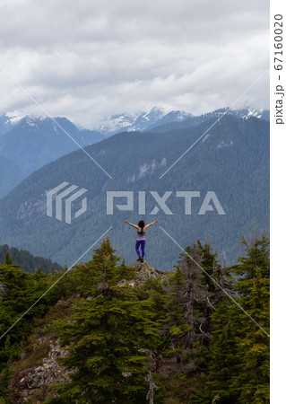 Adventurous Girl on top of a Mountain top with Canadian Nature Landscape 67160020