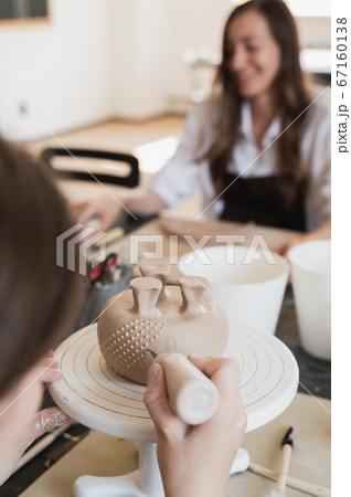 Woman decorating handmade pottery vase close-up 67160138