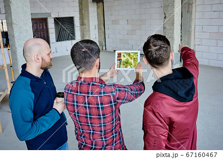 Young designer of interior holding tablet with photo of green plant on screen 67160467