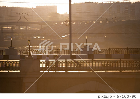 Two young intercultural persons in activewear jogging along bridge by riverside 67160790