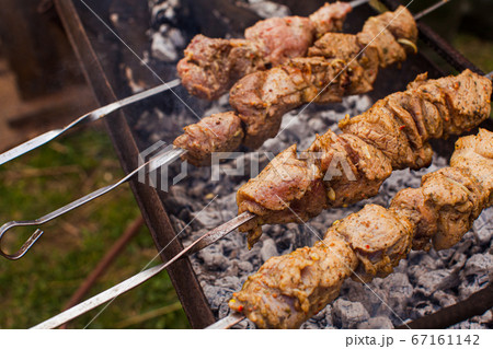 Marinated meat on the metal skewers cooked on the grill 67161142