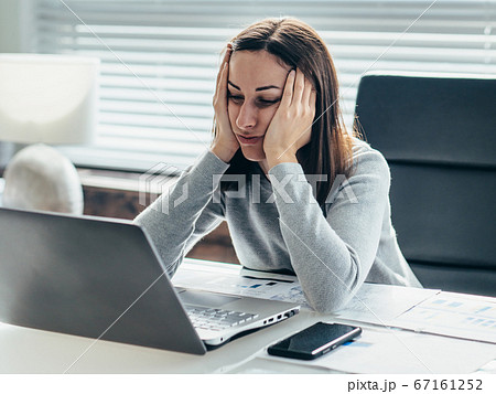 Woman sitting at table with her head leaning on her hands and looking at laptop monitor. Woman sitting at table with her head leaning on her hands and looking at laptop monitor. 67161252