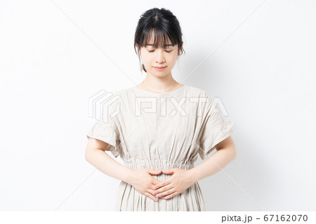 お腹に手を当てる若い女性 お腹に手を当てる若い女性 67162070