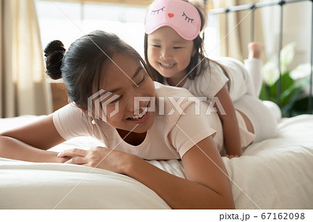 Beautiful vietnamese woman lying on bed with daughter on back. 67162098