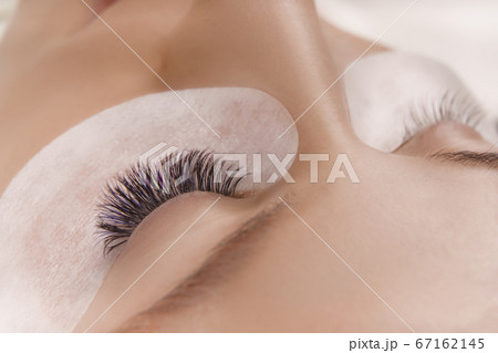 Eyelash Extension Procedure. Close up view of beautiful female eye with long eyelashes, smooth healthy skin. Eyelash Extension Procedure. Close up view of beautiful female eye with long eyelashes, smooth healthy skin. 67162145