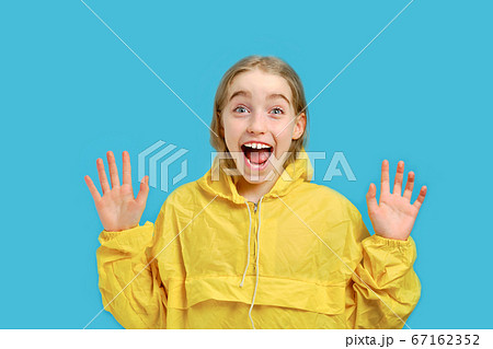 Caucasian little joyful girl in a yellow jacket raised her palms. The Caucasian little joyful girl in a yellow jacket raised her palms. The 67162352