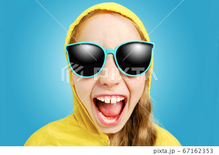 Caucasian joyful girl in a yellow jacket in sunglasses looks at the Caucasian joyful girl in a yellow jacket in sunglasses looks at the 67162353