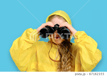 A Caucasian little girl in a yellow jacket looks through large 67162355