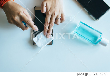 Hands woman cleaning dirty mobile phone on screen,Preventive measures against coronavirus,Covid-19,Work at home,Working from home Hands woman cleaning dirty mobile phone on screen,Preventive measures against coronavirus,Covid-19,Work at home,Working from home 67163536