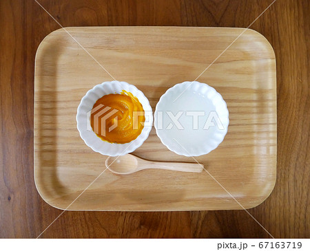 木のトレーの上に置かれたかぼちゃとお粥の離乳食 木のトレーの上に置かれたかぼちゃとお粥の離乳食 67163719