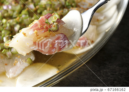 透明な平皿に盛り付けてある鯛とカブのカルパッチョを食べる 67166162